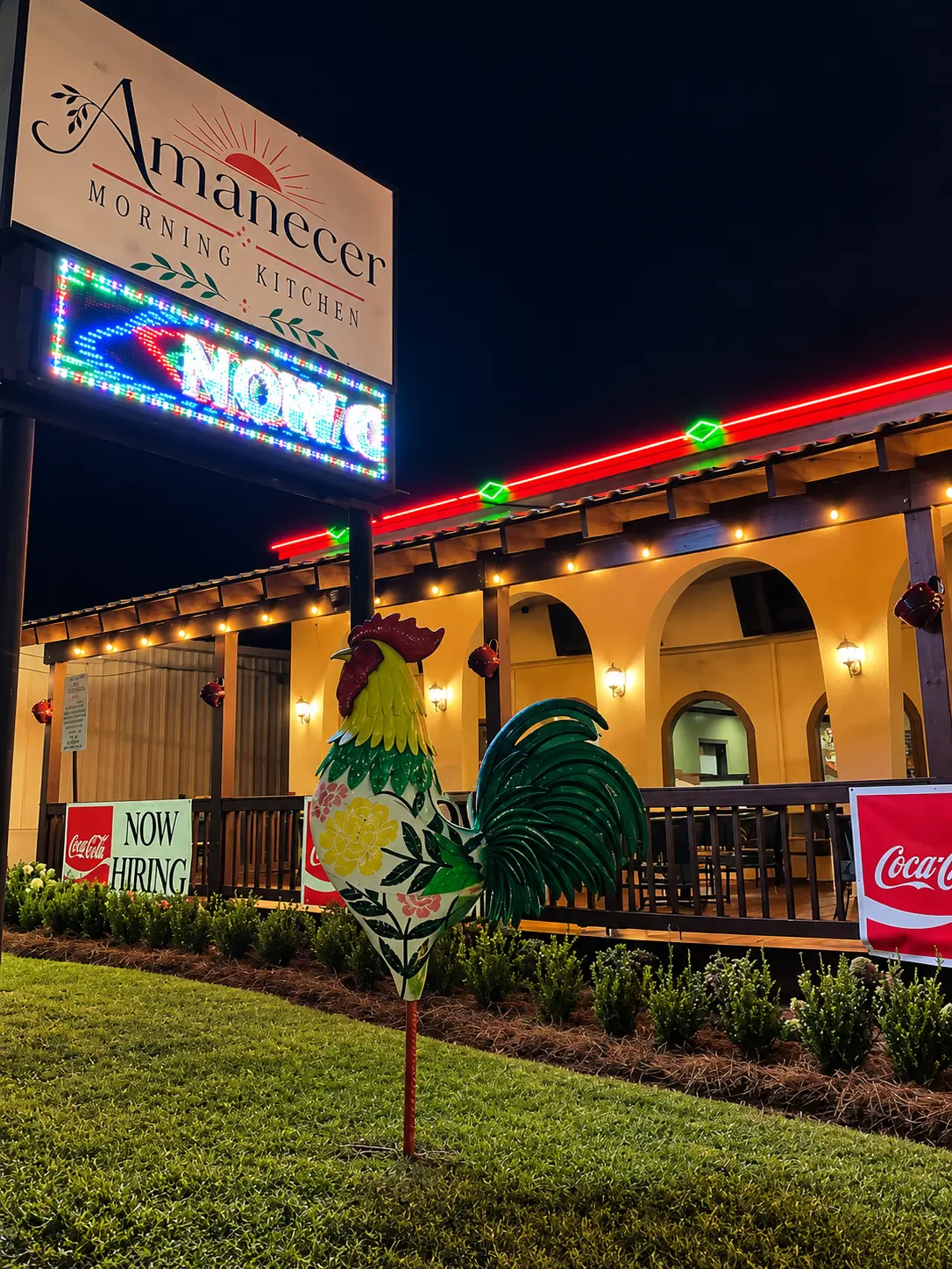Amanecer Morning Kitchen exterior with its illuminated sign, arched patio and colorful rooster