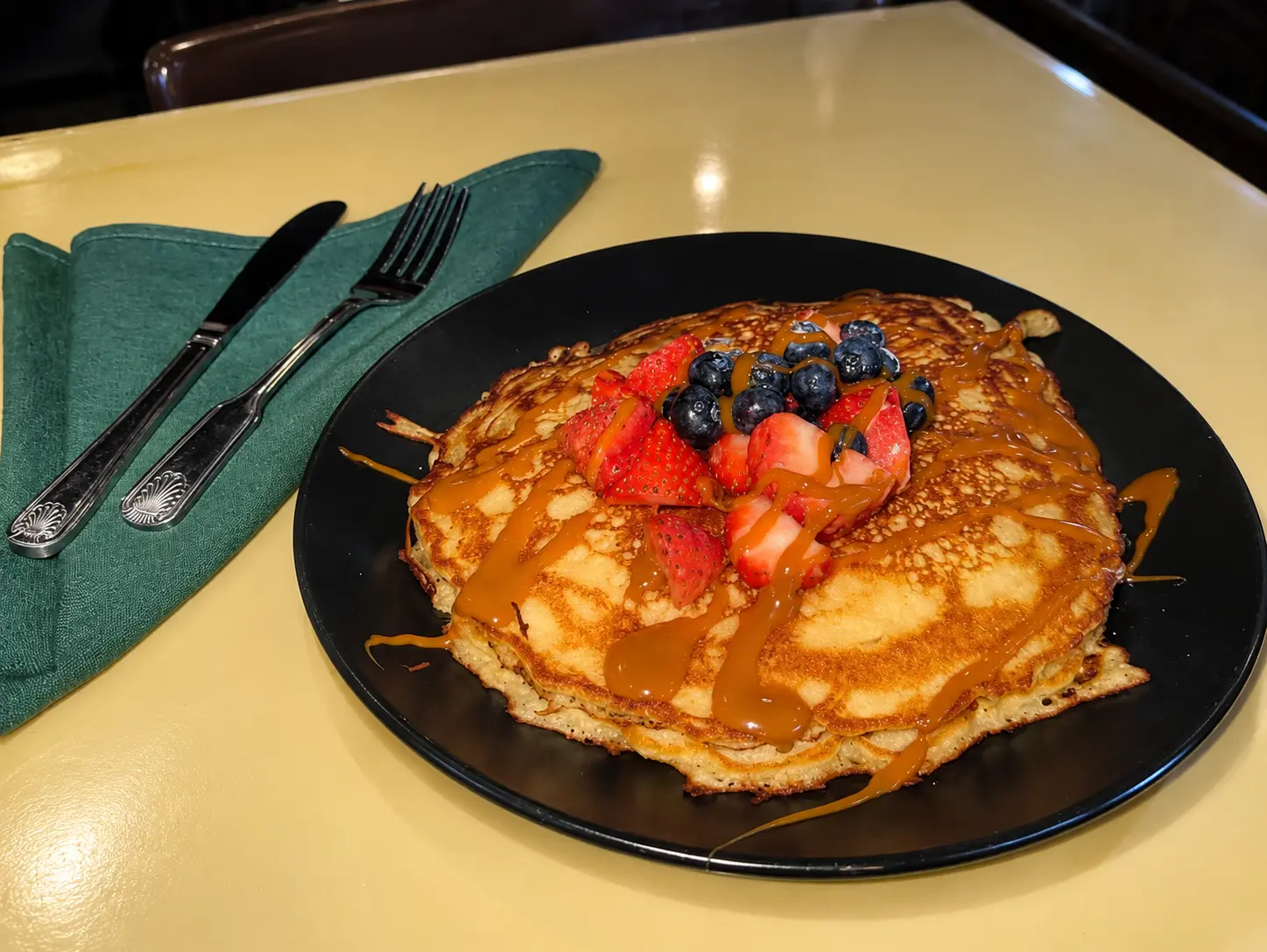 Pancakes topped with strawberries, blueberries and caramel